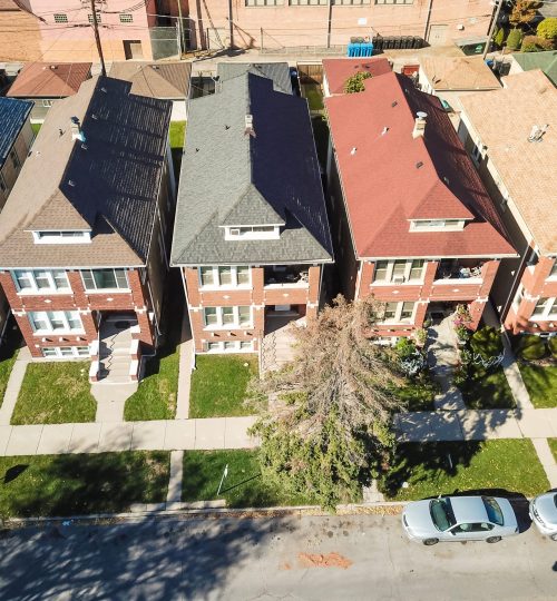 Aerial view classical townhouses in Chicago with garden and detached garage. Colorful condo near local street with front grass lawn yard and car parked on street